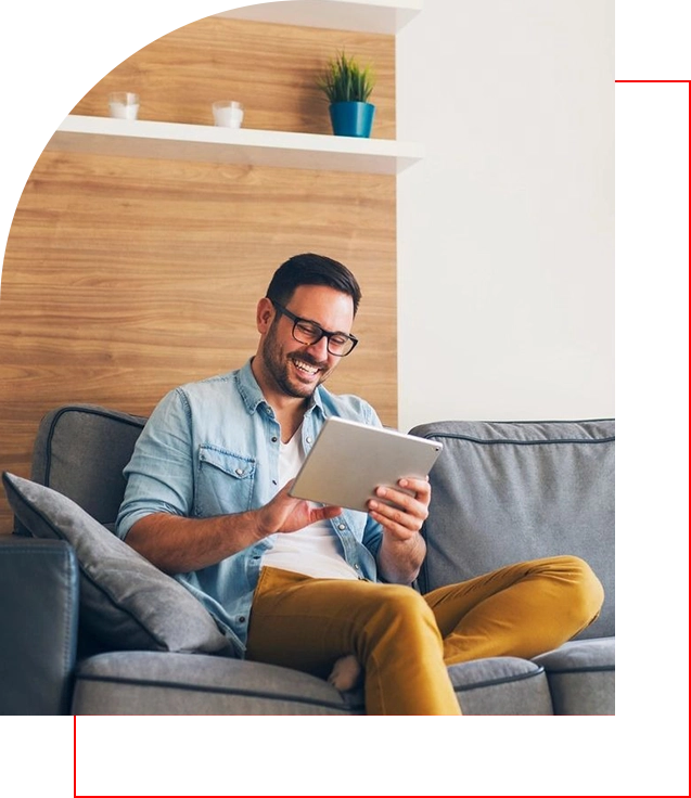 A man sitting on top of a couch holding an ipad.